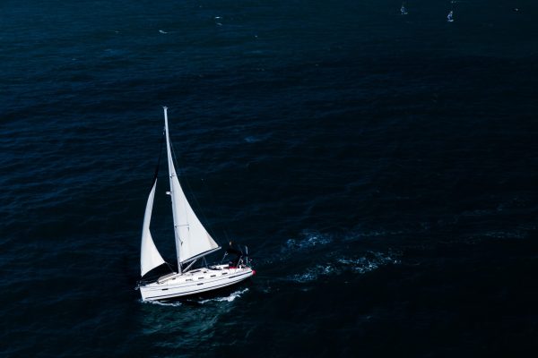 An aerial shot of a small white boat sailing in the ocean